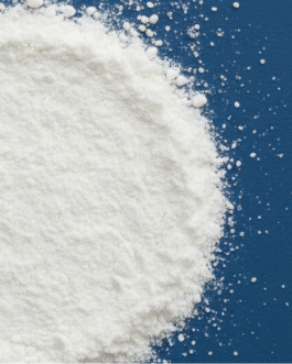 A close-up of a mound of white powder with fine particles scattered on a solid dark blue background.